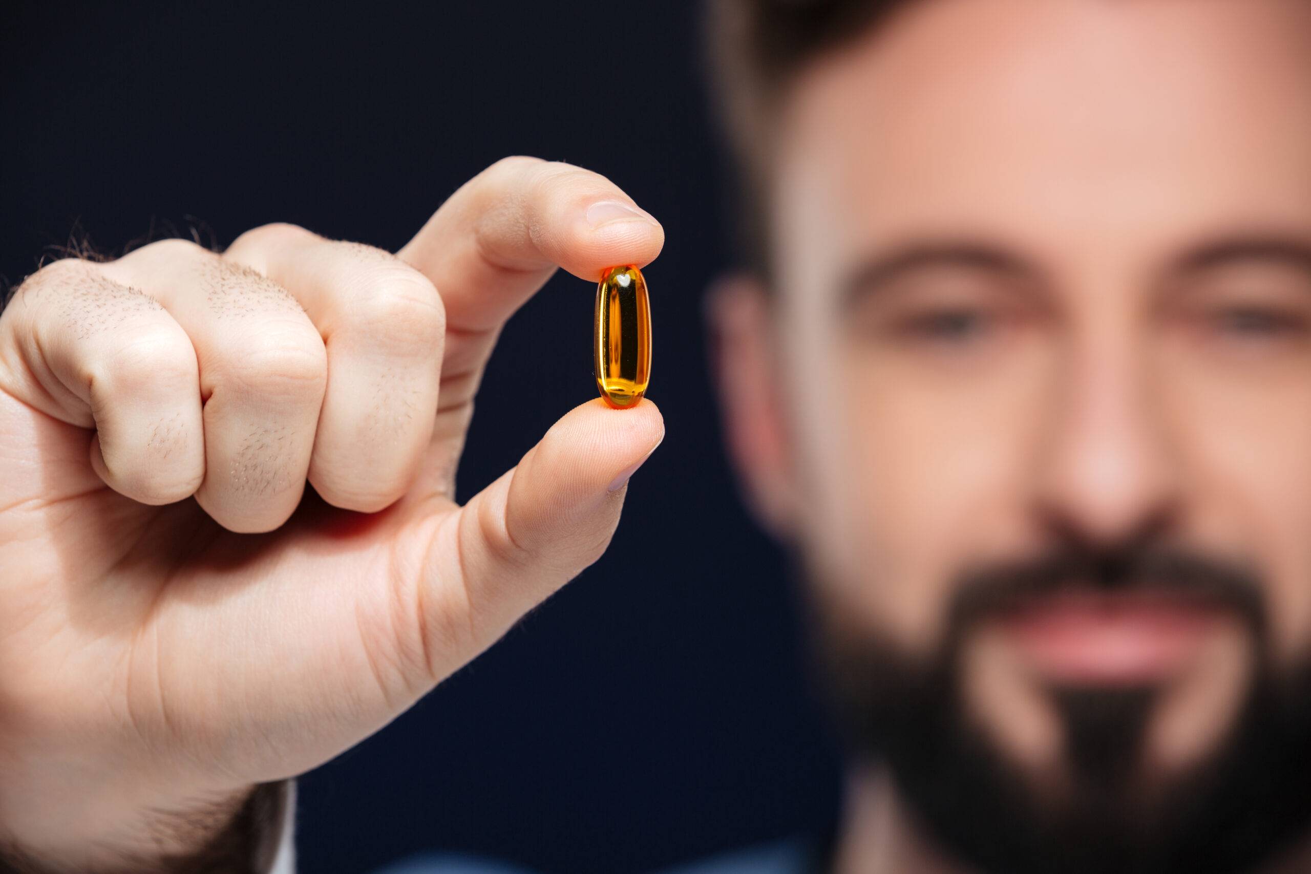 Vyras laiko vitamino D kapsulę 
